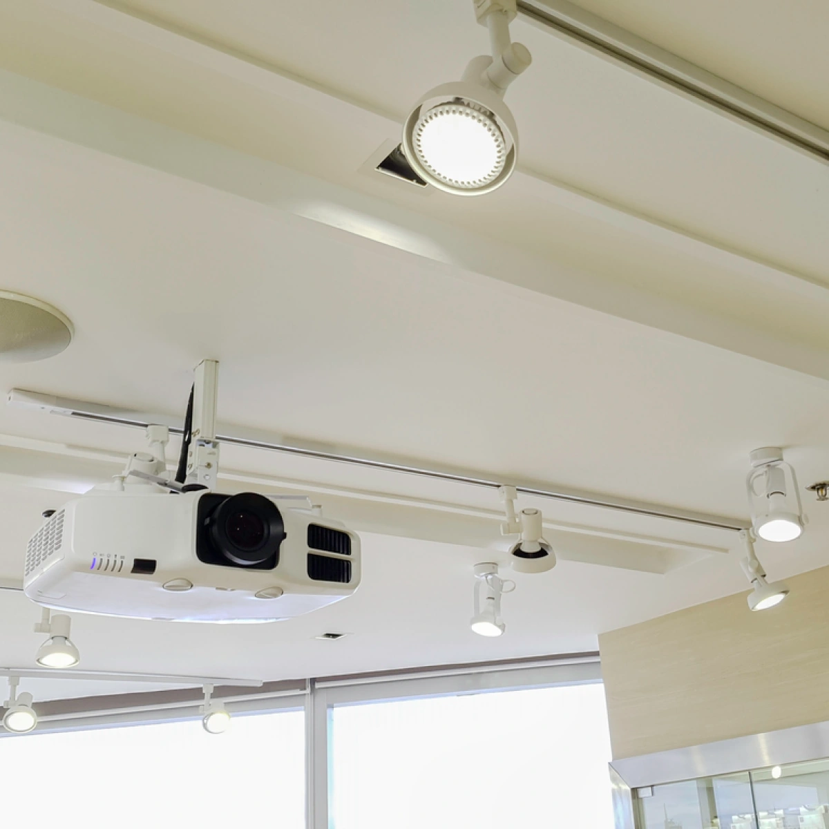 A modern projector and lights on a white ceiling