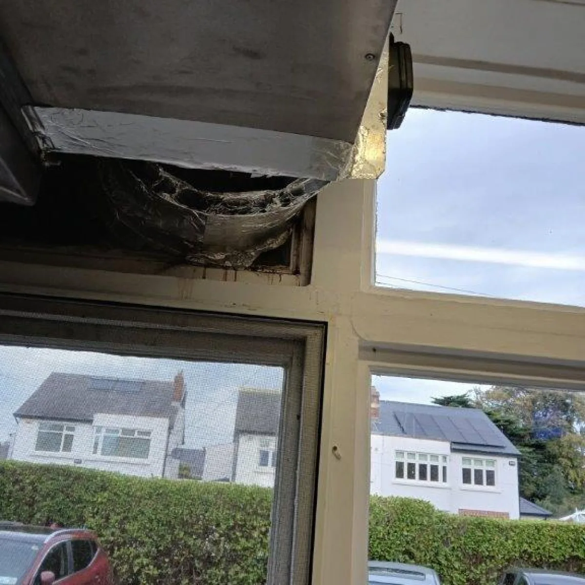 An old, weathered vent above a window, appearing worn and in need of replacement.