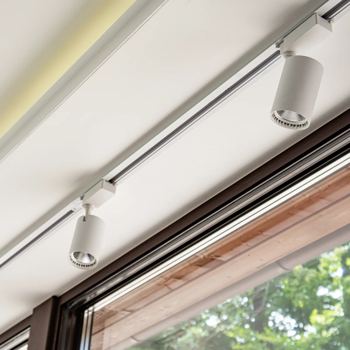 Two modern grey lights mounted on a track, spanning across a white ceiling