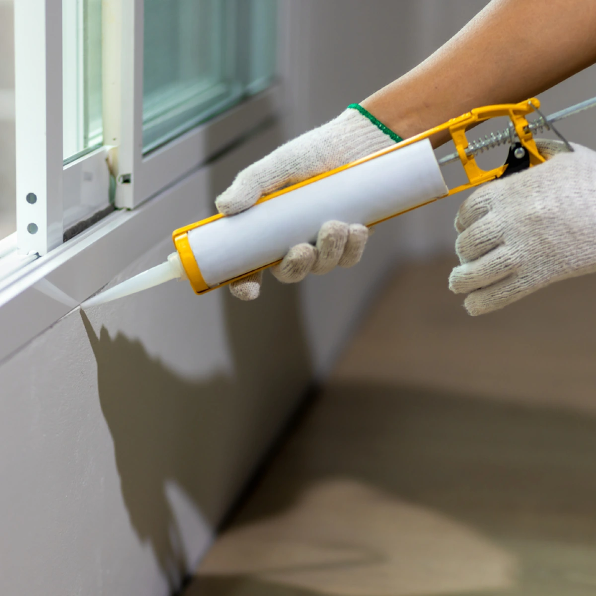 Construction worker using silicone sealant caulk the outside window frame.