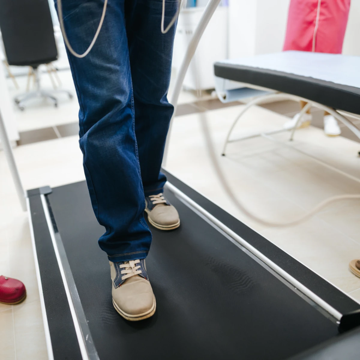 A senior male patient having a cardiac stress test on a treadmill at a clinic - a close up of his legs and feet